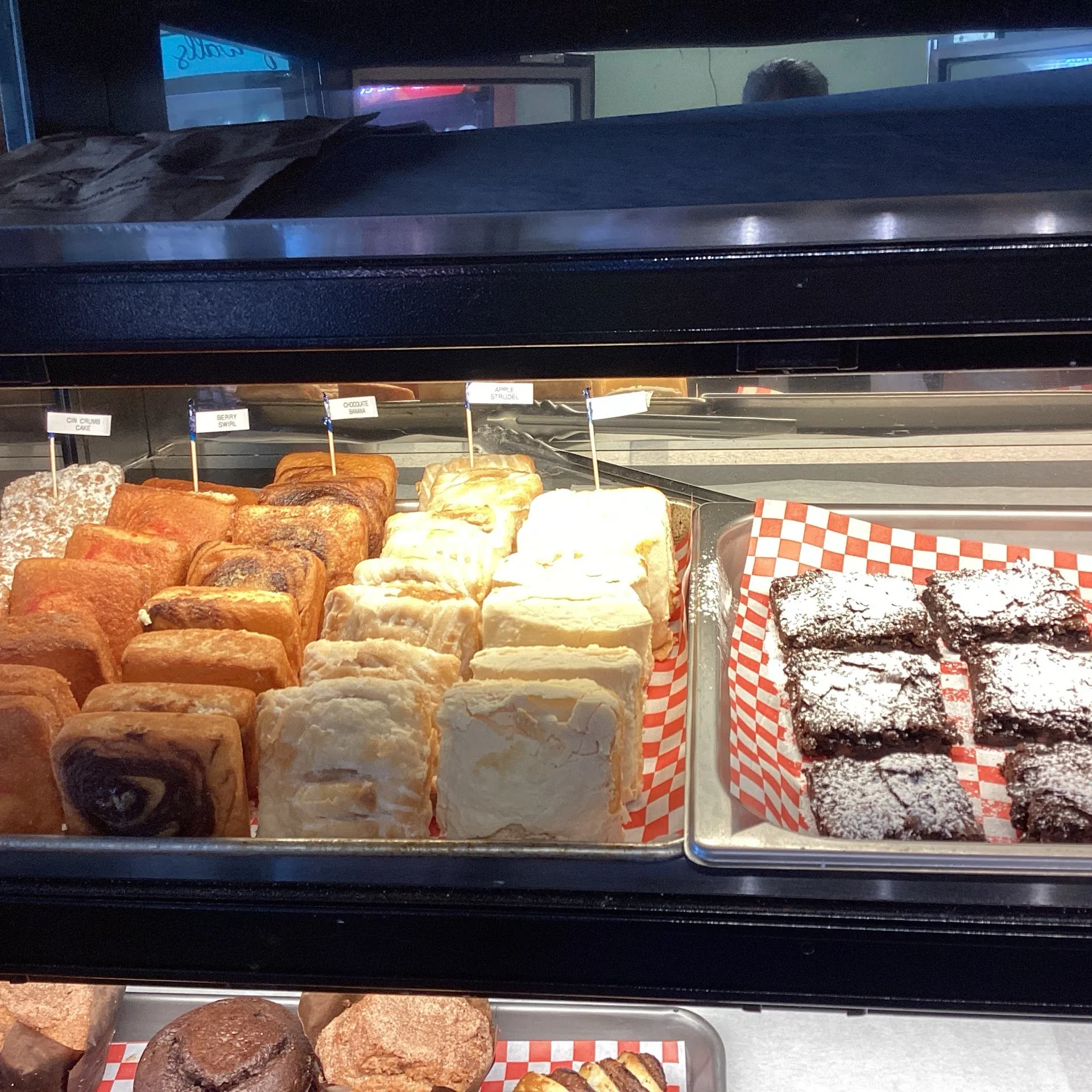 Pastry case with danishes, cinnamon rolls, and brownies inside Baker Market & Deli