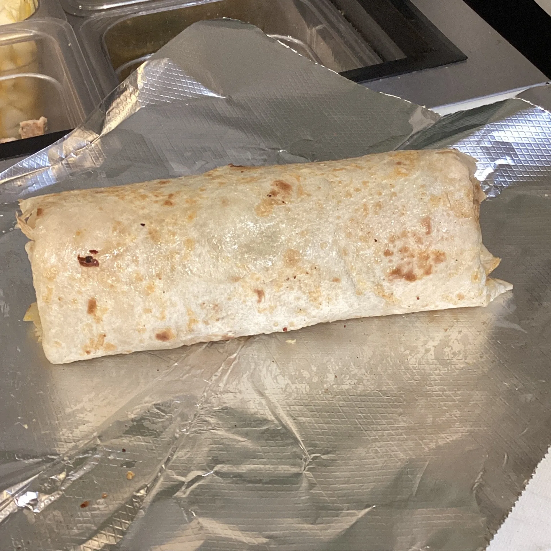 Foil-wrapped breakfast burrito on a prep tray