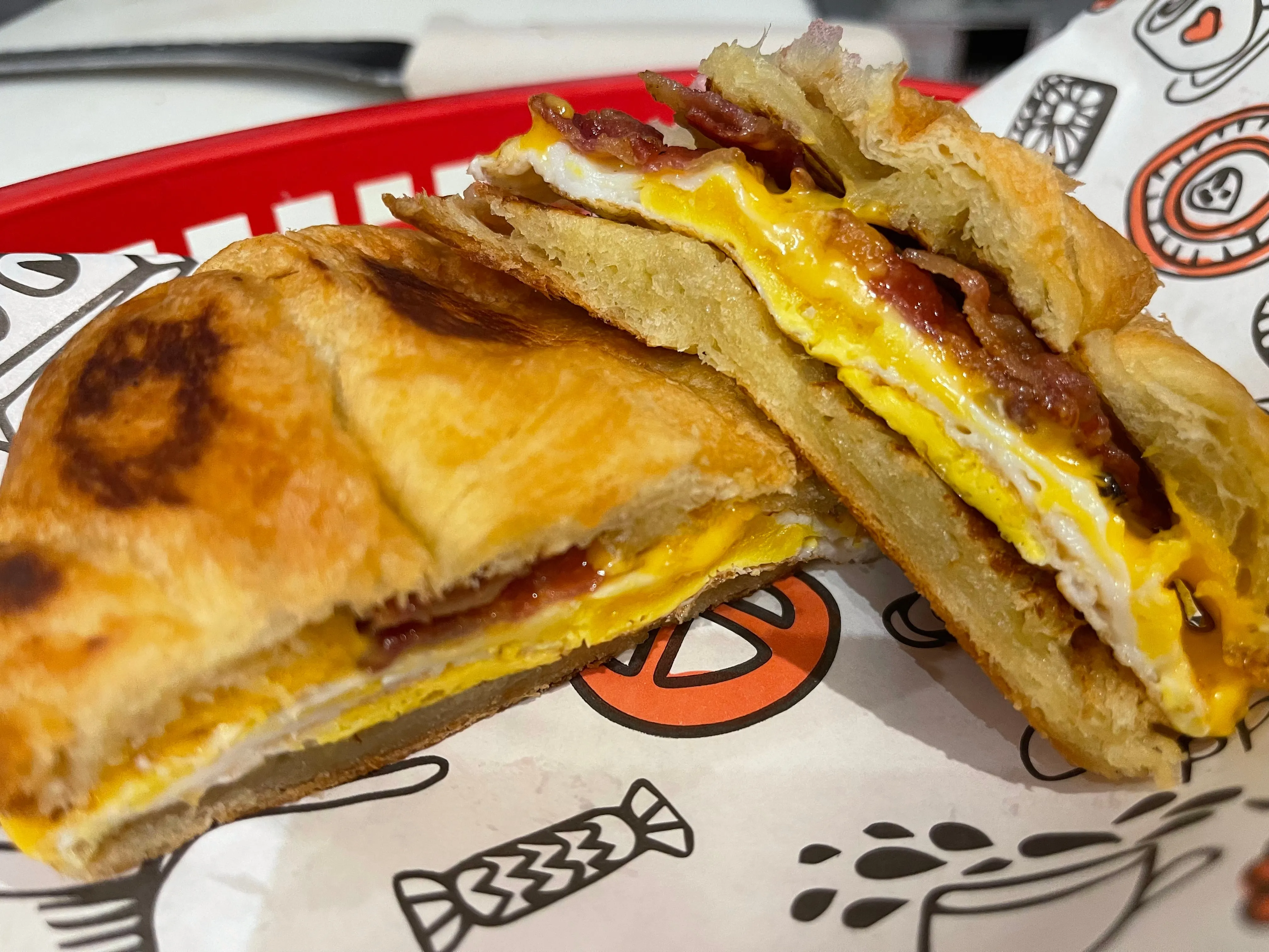 Toasted croissant breakfast sandwich with fried egg, bacon, and melted cheese