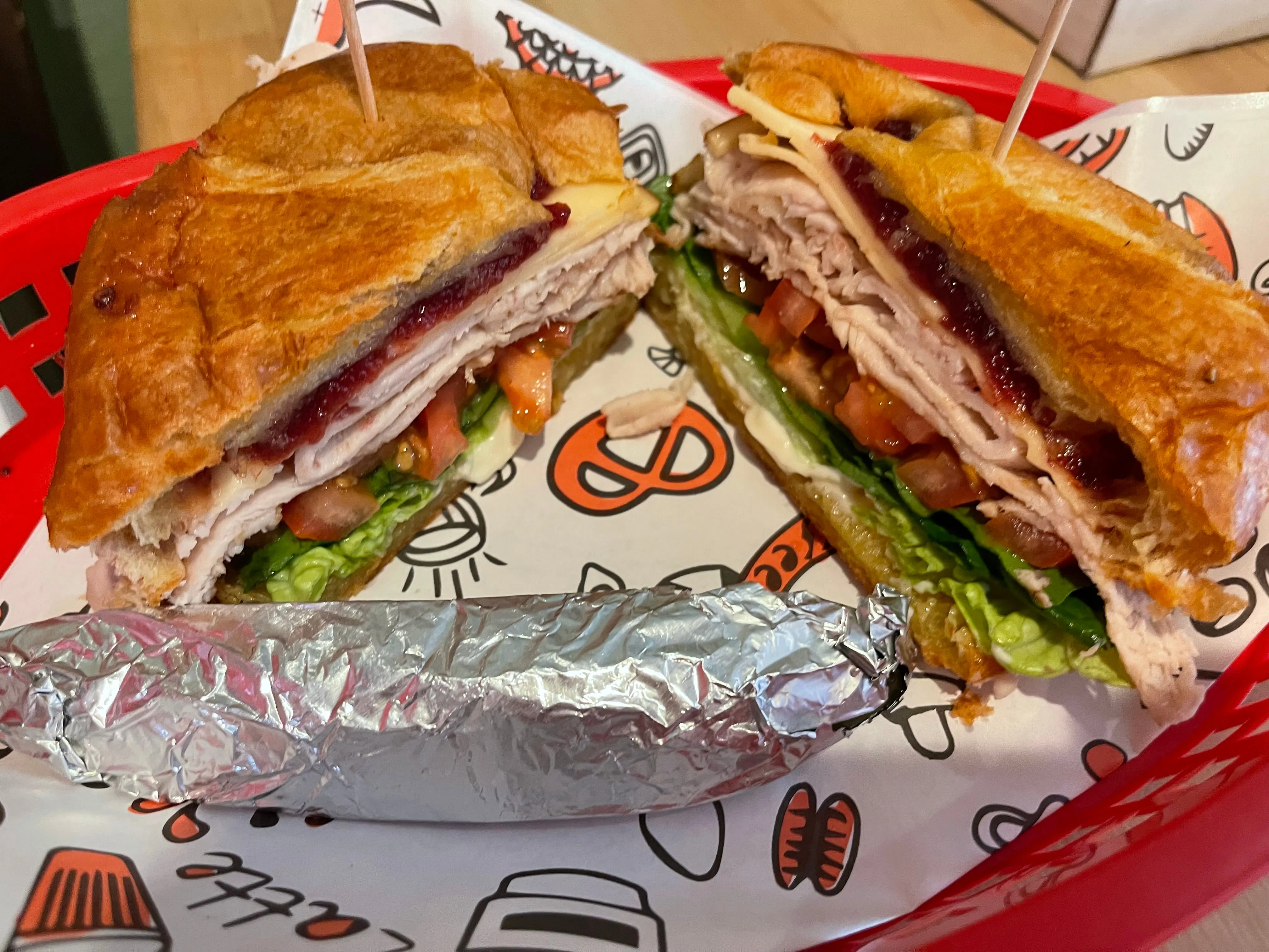 Turkey, cranberry, and gouda sandwich on toasted bread in a deli basket